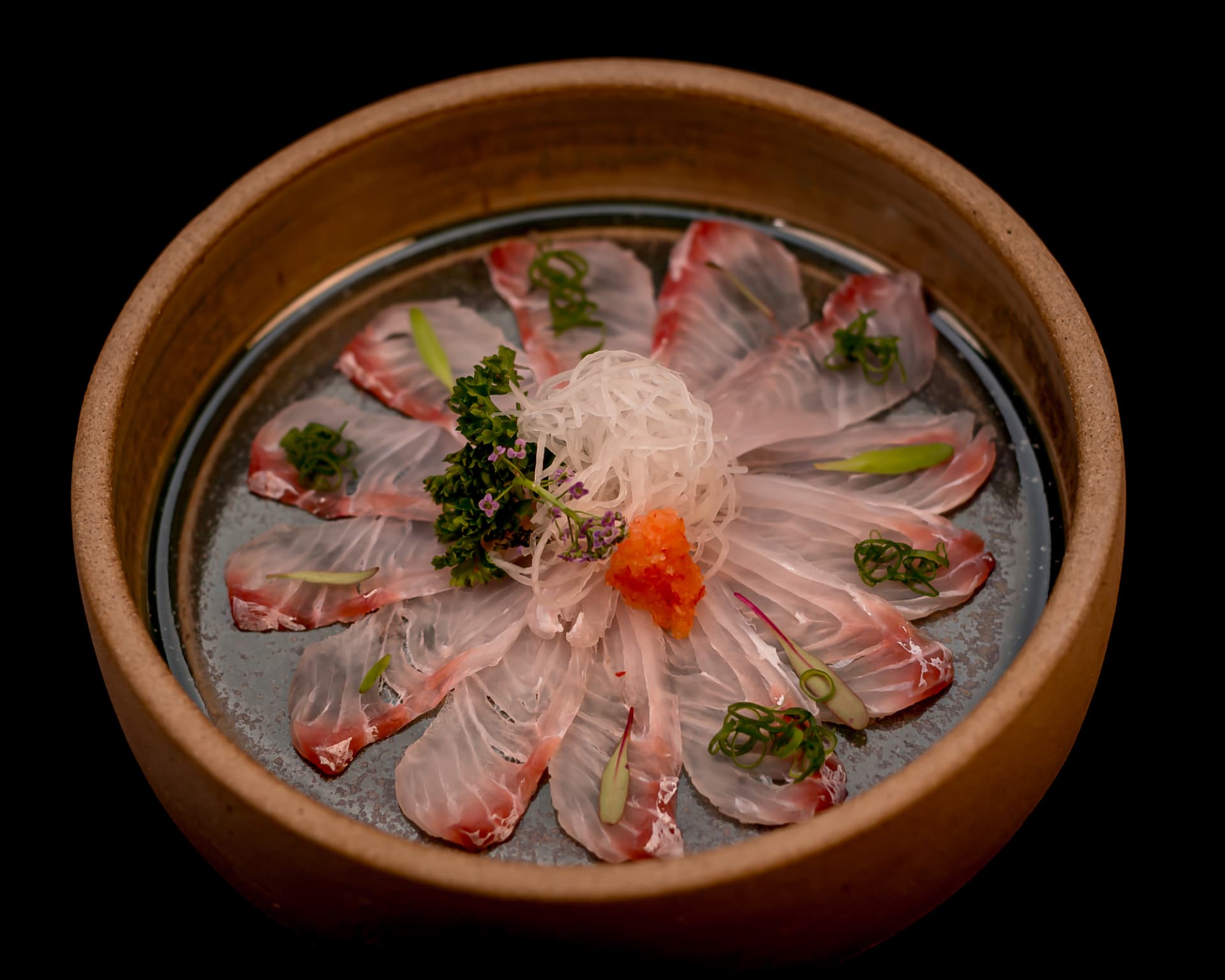 Carpaccio de peixe branco em pétalas com cebolinha, daikon e flor comestível